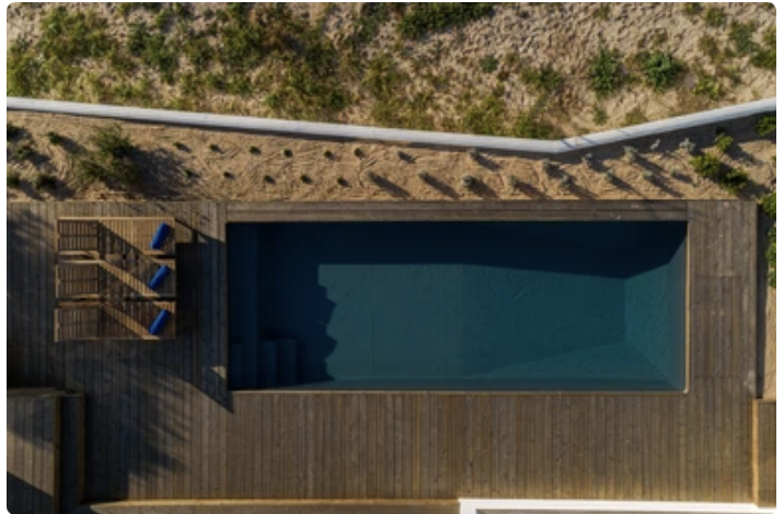Aerial view of a minimalist wooden pool in Comporta, surrounded by sand dunes — pure lines and coastal stillness in Portugal.